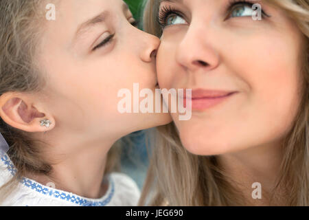 Kleine Tochter küsst eine glückliche Mutter. Close-up Portrait. Stockfoto