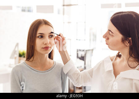 Meister Make-up korrigiert und gibt die Form für Augenbrauen in einem Schönheitssalon. Stockfoto