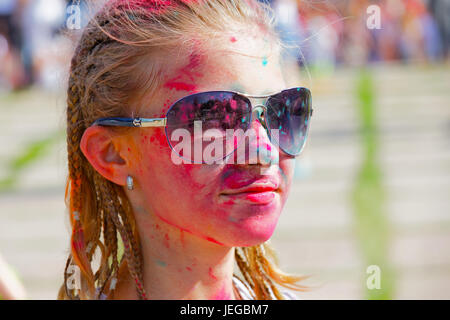 Porträt eines fröhlichen Mädchens in Flecken von der trockenen Farbe auf einem Festival der Farben Stockfoto