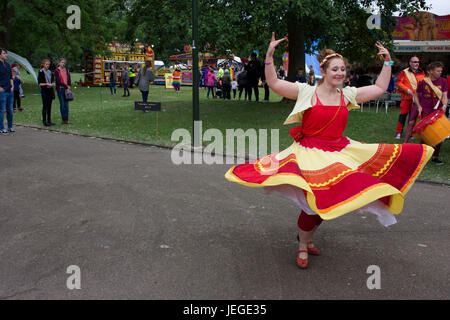 Junge Frau im Flamenco Stil mit roten und gelben Kleid tanzen auf LGBT pride Event in Hanley Park gekleidet, Stoke-on-Trent, Staffordshire, Großbritannien, 24. Juni 2017. Die Leute und Park im Hintergrund. Stockfoto