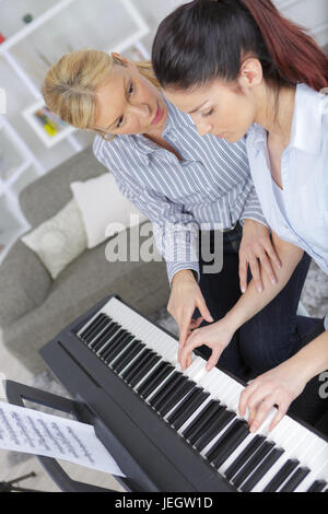 erfahrene weibliche Klavier Meisterhand hilft den Studenten Stockfoto