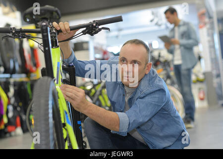 Man prüft Fahrrad vor dem Kauf im Sportgeschäft Stockfoto