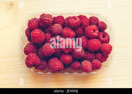 Draufsicht der reife Himbeeren in Kunststoff-Container-Box auf Holztisch, getönten Retro Bild Stockfoto