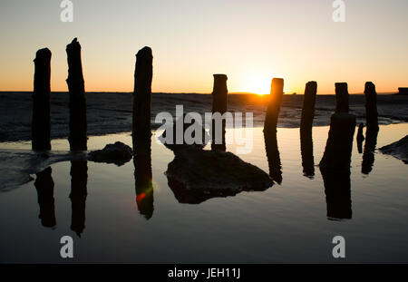 Grange-über-Sands Strand Sonnenuntergang, in der Nähe des Lake District. Die tiefstehende Sonne Schatten zu schaffen. Holzpfähle kann für eine Fischfalle verwendet worden sein. Gezeiten-Mündung. Stockfoto