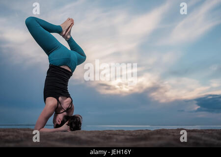 Voller Länge Schuss jungen Frau Sirsasana üben. Stockfoto