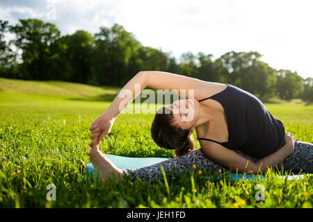 Frau praktiziert Yoga Asana im Park am Morgen. Stockfoto