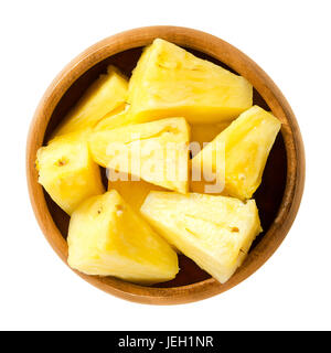 Ananasstücke in Holzschale. Ananas Comosus, essbare Multiple Frucht einer tropischen Pflanze, bestehend aus verschmolzen Beeren. Gelbem Fruchtfleisch. Foto. Stockfoto