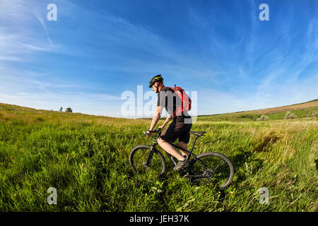 Junge Radfahrer fahren Berg Radfahrer gegen schönen Sonnenaufgang auf dem Lande. Stockfoto