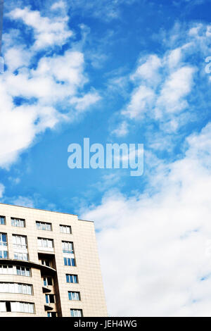 Hochhaus auf dem Hintergrund des weißen flauschigen Wolken auf einem klaren blauen Himmel. Stockfoto