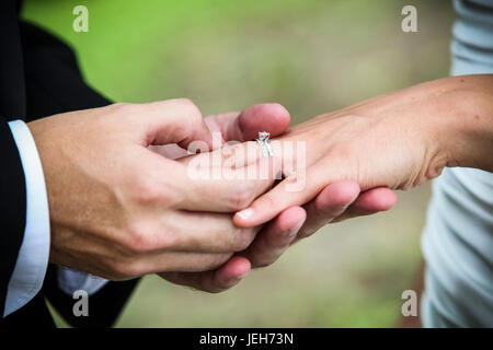 Ein Bräutigam steckt einen Ring auf seine Braut Finger während einer Trauung; Ontario, Kanada Stockfoto