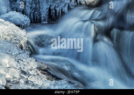 Eiszapfen und blau schattierten Kaskaden auf einem kleinen Wasserfall; Enfield, Neuschottland, Kanada Stockfoto