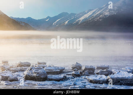 Die Sonne Scheint Durch Den Nebel Auf Niedriger Höhe, Der In Warmes Licht Gegossen Wird, Entlang Des Turnagain Arms Und Des Seward Highway, Das Meereis Bedeckt Den Ozean Im Vordergrund... Stockfoto