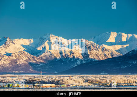Blick Auf Die Innenstadt Von Anchorage Im Winter Und Die Schneebedeckten Chugach Mountains Dahinter Vom Point Mackenzie Aus Gesehen, Die Skies Im Hintergrund Klar Und ... Stockfoto