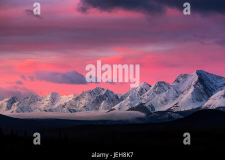 Dramatisch leuchtenden Himmel bei Sonnenaufgang mit Schnee bedeckten Bergen und Nebel im Tal; Kananaskis Country, Alberta, Kanada Stockfoto