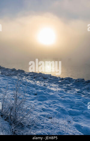 Die Sonne Scheint Durch Den Nebel Auf Niedriger Höhe, Der In Warmes Licht Gegossen Wird, Entlang Des Turnagain Arms Und Des Seward Highway, Das Meereis Bedeckt Den Ozean Im Vordergrund... Stockfoto