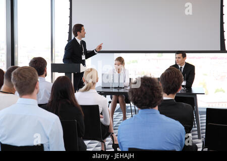 Referent bei Business-Konferenz in der Nähe von hellen Bildschirm und Publikum Stockfoto