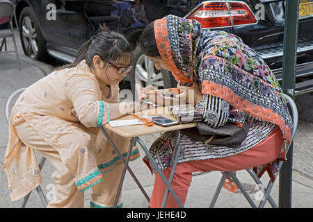 Eine islamische Frau in traditioneller Kleidung schmückt ein junges Mädchen Hand mit Henna, Eid Al Fitr Urlaub markiert das Ende auf Ramadan zu feiern. Stockfoto