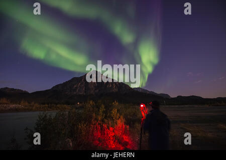 Ein Fotograf fängt die Aurora Borealis, wie es über Mt. Dillon in der Brooks Range nördlich von Wiseman, Arktis, Alaska, USA tanzt Stockfoto