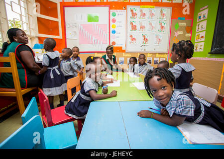 Kleinen Kindern in einem Klassenzimmer mit einem Lehrer auf die Schätze christlichen Vorschule; Kampala, Uganda Stockfoto