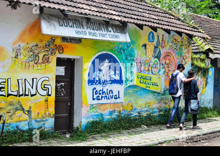 Junge indische paar zu Fuß auf River Road mit Wandmalereien, Fort Cochin; Kochi, Kerala, Indien Stockfoto