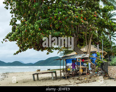 Ein Mann steht in seiner Heimat Shanty am Strand entlang dem Golf von Thailand; Ko Samui, Chang Wat Surat Thani, Thailand Stockfoto