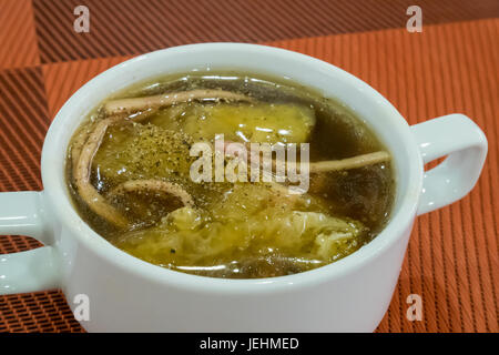 Die weiße Keramikschale aus köstlichem chinesischem geschmorten Fischroh in roter Soße auf roter Dish-Matte. Stockfoto