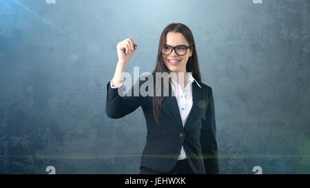 Junge schöne Geschäftsfrau mit Stift auf dem Bildschirm schreiben. Stockfoto