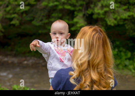 Babymädchen auf etwas in der Mutter Armen Stockfoto