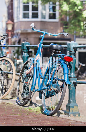 Geparkten blauen Fahrrad auf einem Geländer im historischen Grachtengürtel, Amsterdam, Niederlande Stockfoto