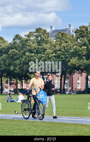 AMSTERDAM-AUG. 24, 2014. Kaukasisches Paar Spaziergänge auf einem sonnenbeschienenen Museumsplatz. Ein beliebter touristischer Platz, wo sich mehrere berühmte Museen befinden. Stockfoto