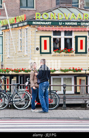 AMSTERDAM, 26. AUGUST 2014. Ein Paar, das romantische Zeit in der Nähe des Bootsanlegepunkts hat. Der historische Grachtengürtel mit schönen alten Häusern und Kanälen. Stockfoto