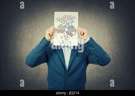 Geschäftsmann, bedeckte sein Gesicht mit einem Papier mit Gehirn aus Getriebe Skizze bildet eine Complet Coloruful Gehirn gemacht. Das Konzept der Righ Lösung finden. Stockfoto