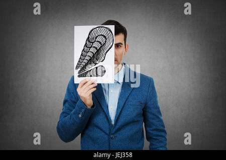 Porträt eines traurigen Geschäftsmann, versteckt die Hälfte seines Gesichts mit ein Weißbuch mit Fragezeichen gezeichnet. Traurig Student versteckt Gesicht mit vielen Fragen Mark. Stockfoto