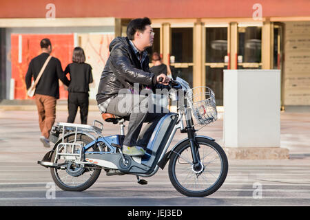 PEKING – ÜLG. 17, 2011. Mann auf dem Elektrofahrrad in Peking. Derzeit kaufen viele Einwohner Pekings batteriebetriebene Fahrräder, um Staus zu vermeiden Stockfoto