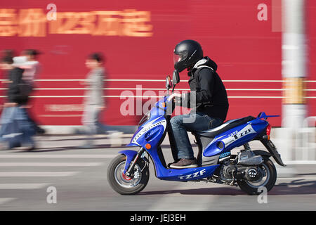 PEKING – ÜLG. 25, 2011. Mann, der auf einem Roller in Peking rauscht. Derzeit bevorzugen viele Einwohner Pekings Roller statt Autos, um Stau zu vermeiden. Stockfoto