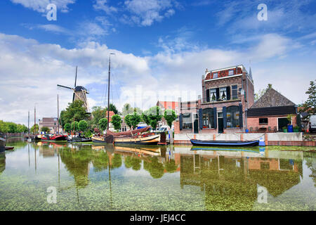 Glatte grüne Kanal mit festgemachten Boote und monumentale Häuser in der alten Stadt Gouda, Niederlande. Stockfoto