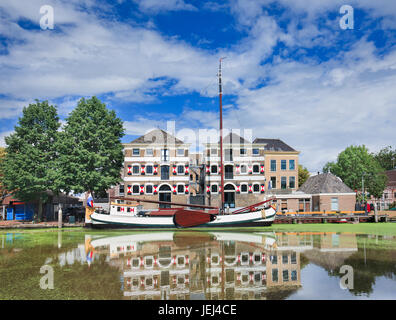 Stattliche monumentalen Herrenhaus mit einem weißen festgemachten Boot spiegelt sich in einem Kanal. Stockfoto