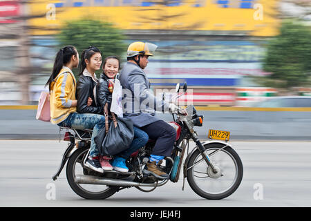 GUANGZHOU-FEB. 22, 2012. Motorrad-Taxi mit drei jungen fröhlichen Mädchen auf der Straße mit Bewegung verschwommen Hintergrund. Stockfoto