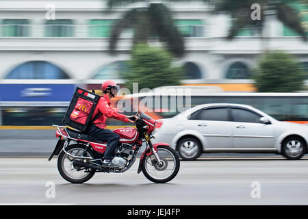 GUANGZHOU – FEB. 22, 2012. McDonald Liefermotorrad auf der Straße mit Palmen in Bewegung Unschärfe auf dem Hintergrund. Stockfoto