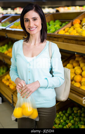 Porträt einer lächelnden Frau kaufen Orangen Stockfoto