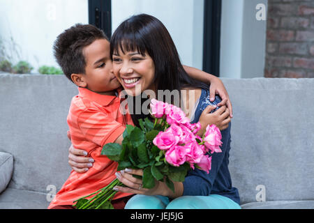 Niedliche Sohn umarmt seine Mutter nach ihrem Blumen schenken Stockfoto
