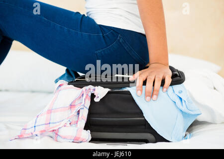 Frau sitzt auf ihrem übervoll-Koffer Stockfoto