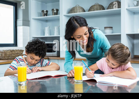 Gute Mutter ihren Kindern Hausaufgaben zu helfen Stockfoto