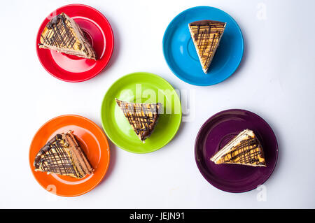 Karamell-Kuchen-Scheiben auf bunten Tellern serviert Stockfoto