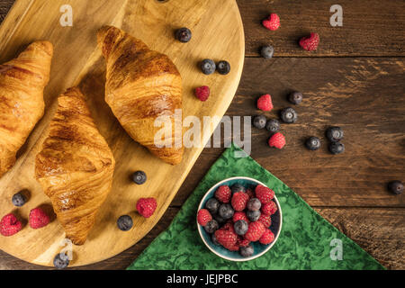 Knusprige französische Croissants mit frischen Himbeeren und Heidelbeeren Stockfoto