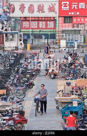 PEKING - 10. JULI 2015. Mann mit Fahrrad verlässt einen Parkplatz. Auch wenn die rasante Vermehrung von Autos in China das Fahrrad nach wie vor das größte Transportmittel ist. Stockfoto