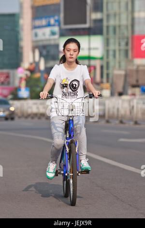 PEKING - 24. JULI 2015. Junge Mädchen auf dem öffentlichen Fahrrad. Fahrradnutzung ermöglicht die kurzfristige Anmietung, es ist ein sehr beliebter Transportmodus. Stockfoto