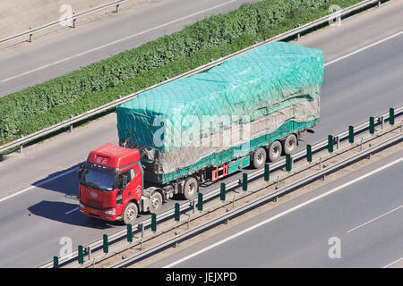 PEKING - 30. JUNI 2015. FAW-LKW mit Anhänger auf einer Schnellstraße. Die FAW Group ist ein chinesisches, staatliches Automobilunternehmen mit Hauptsitz in Changchun. Stockfoto