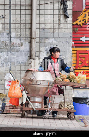 CHONGQING - 30. OKTOBER 2014. Weibliche Verkäuferin verkauft Straßennahrung. Chongqing ist ein Paradies für Speisen wegen verschiedener exotischer, würziger Snacks. Stockfoto