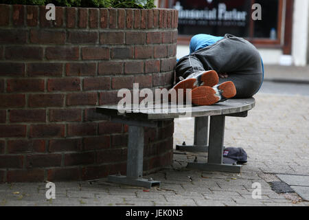 Obdachlosen schlafen auf einer Bank in Chichester, West Sussex, UK. Stockfoto